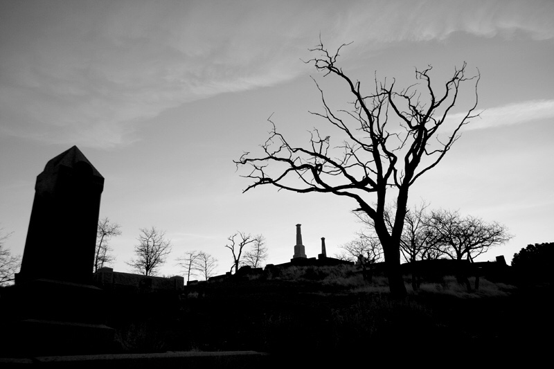 A black and white photo of a graveyard at dusk.